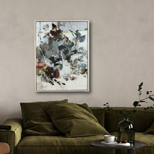 Abstract nature painting on a wall above a green sofa with a small table and decor items.