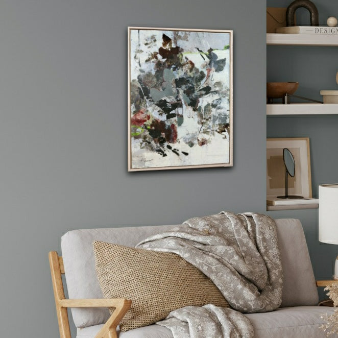 Living room with a gray sofa, abstract painting on the wall, and shelves with decorative items.