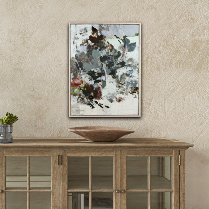 Abstract painting of leaves on a wall above a wooden console table with a decorative bowl.