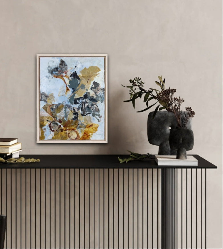 Modern interior with earth toned abstract nature art on a wall above a black console table.