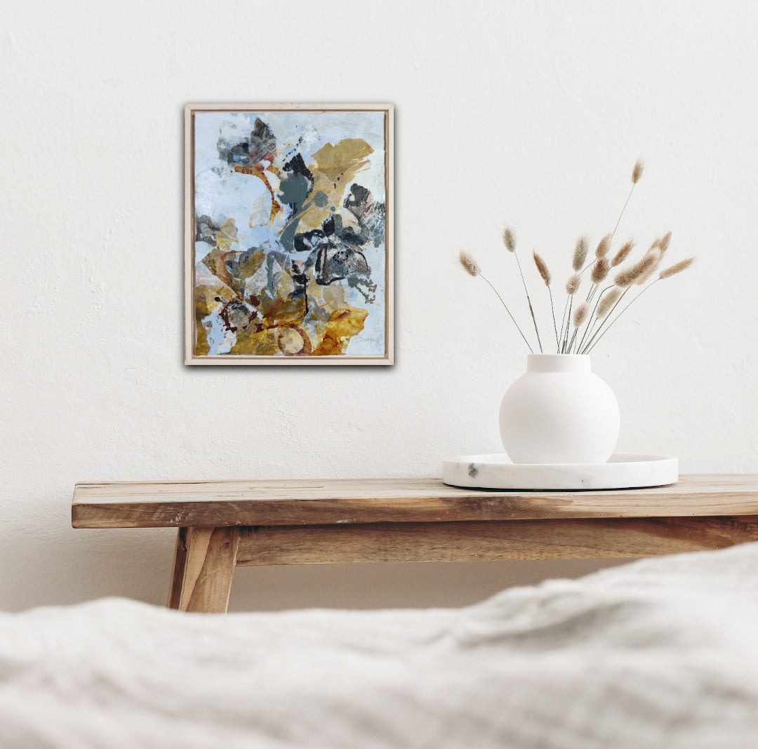 Abstract nature mixed media painting on a wall above a wooden shelf with a vase and dried plants.