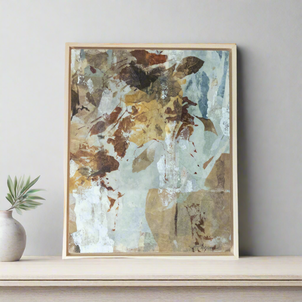 Framed abstract art piece on a shelf with a plant in the background